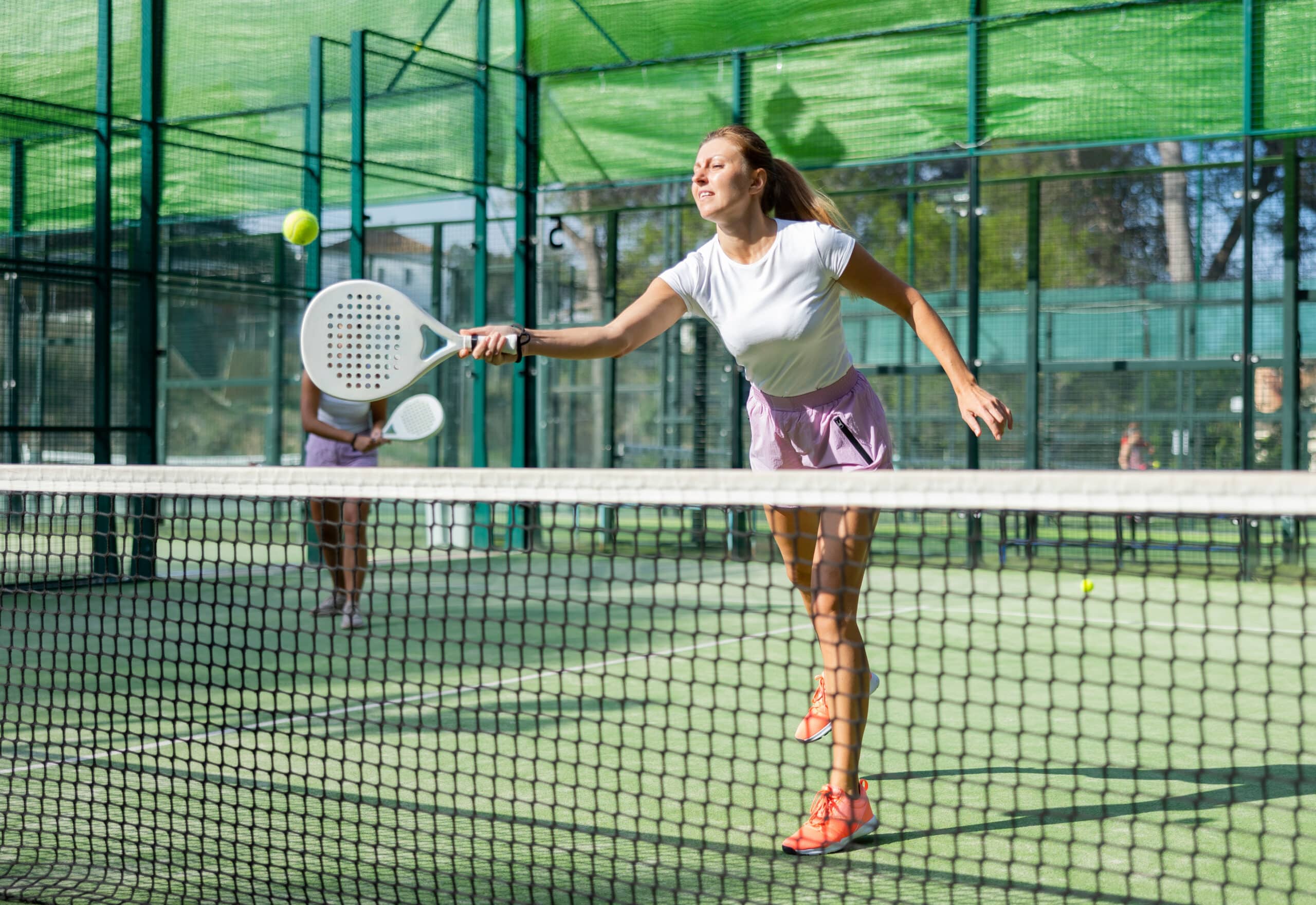 Active womans with enthusiasm playing padel on tennis court